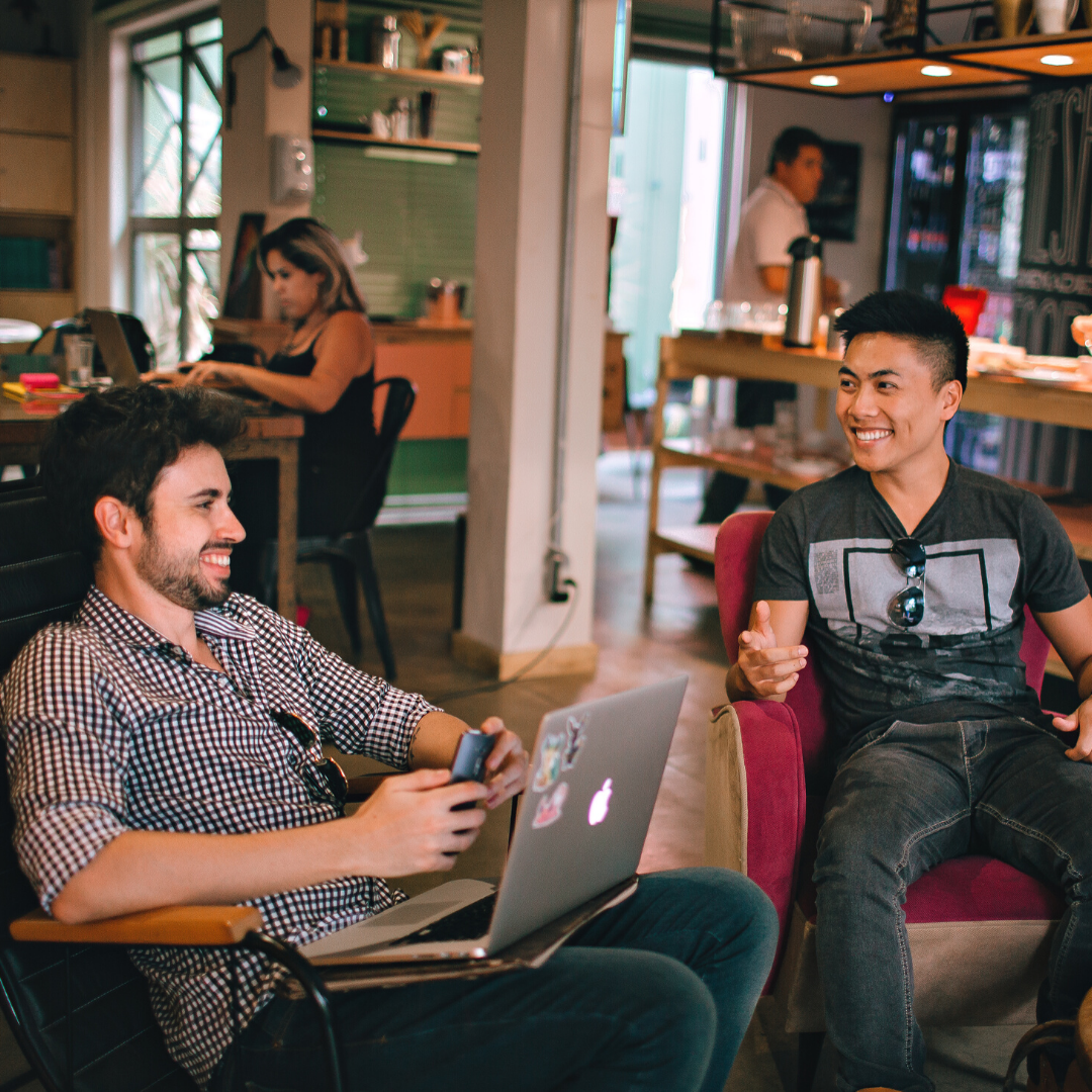 Employee Appreciation | two friendly men sitting in armchairs in a work environment smiling at eachother