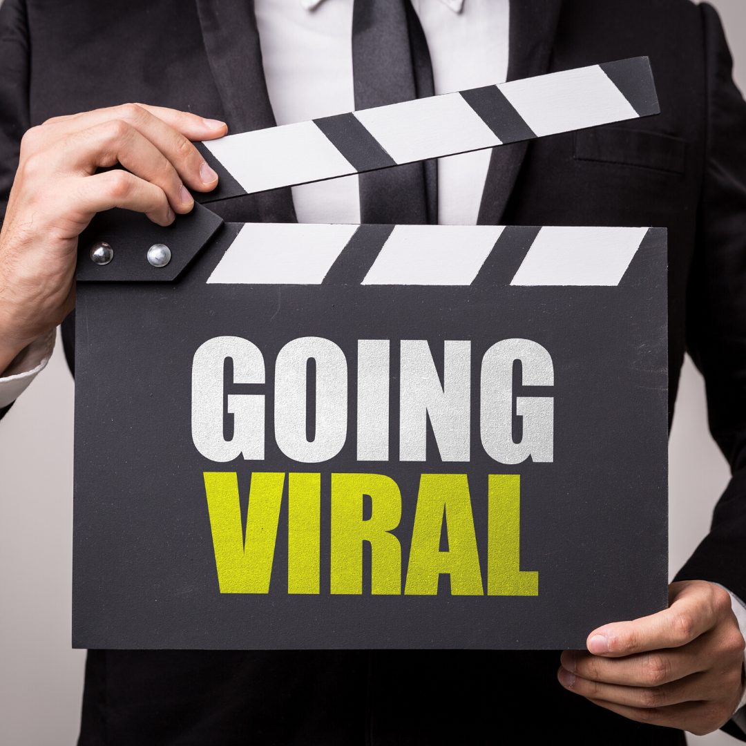 a man wearing a black suit learning how to go viral holding a clapper board